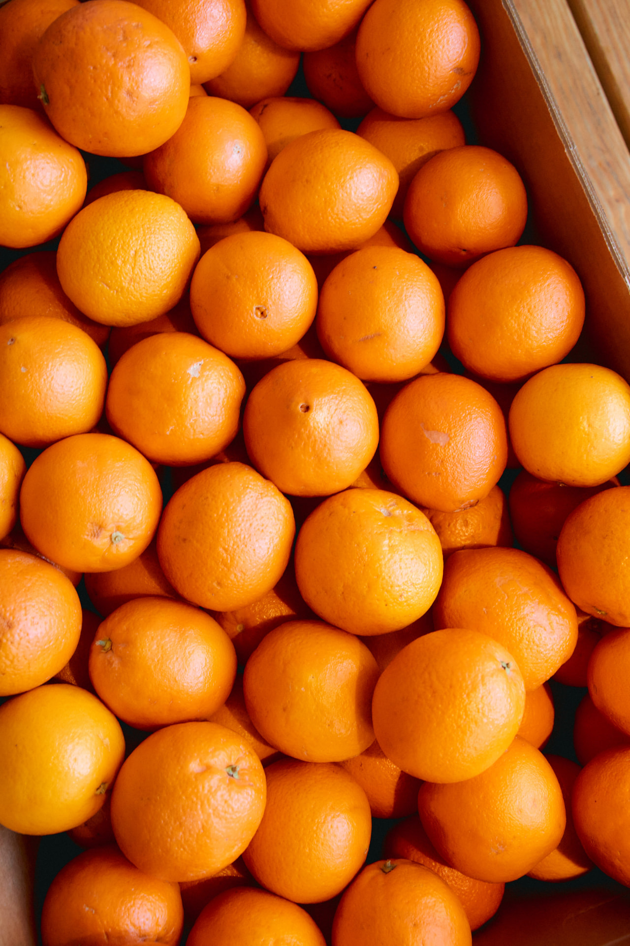 A wooden crate packed with bright ripe oranges