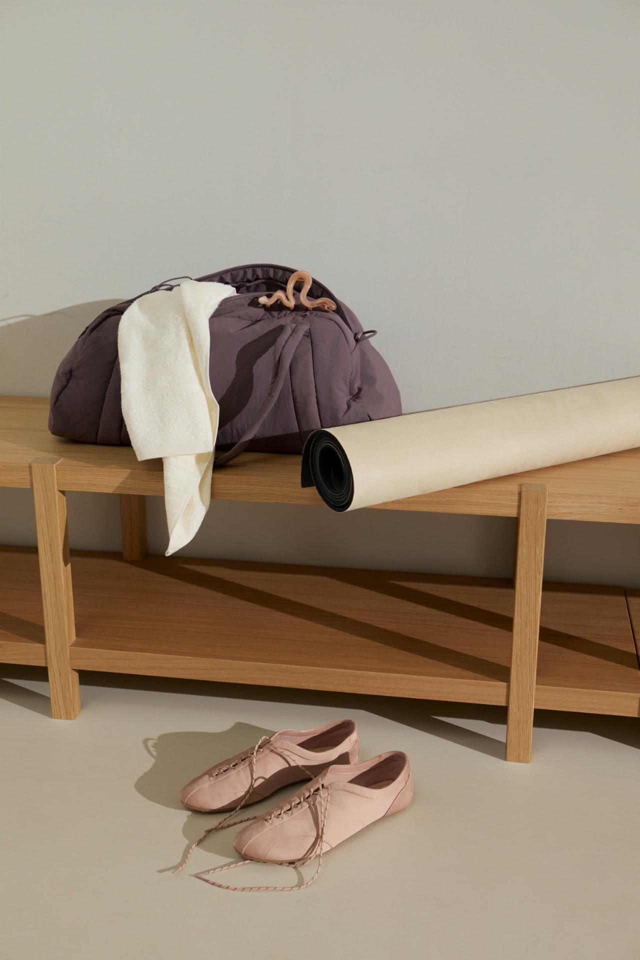 Kit bag, towel, rolled mat and trainers resting by a wooden bench